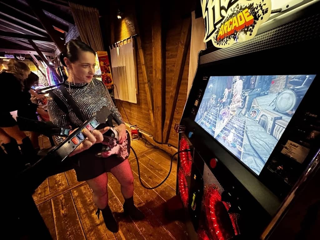 1 person vor der arcade maschine guitar hero mit jeweils einer gitarre in der hand.