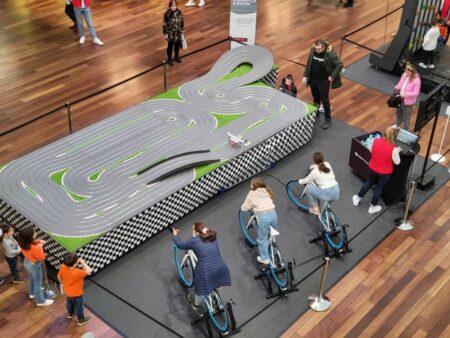 grosse slotcar rennbahn in einem einkaufszentrum. 3 personen fahren auf dem fahrrad...