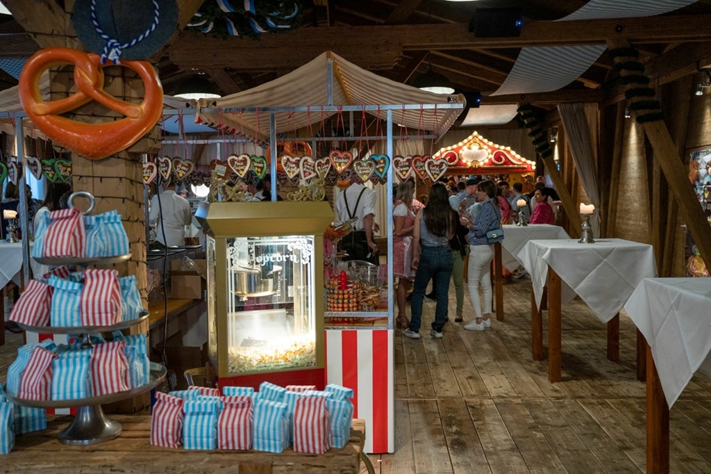 beleuchtete popcornmaschine an einem okotberfest. maschine mit lebkuchenherzen behangen.