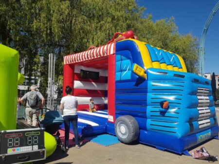 Aufblasbare Hüpfburg in Form eines bunten Foodtrucks mit Kindern und Erwachsenen bei sonnigem Wetter.