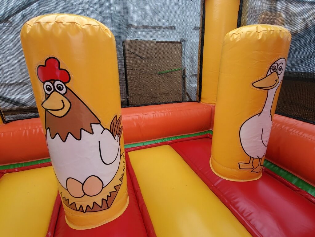 Nahaufnahme zweier aufblasbarer Säulen mit einem Huhn und einer Gans im Inneren der Hüpfburg.