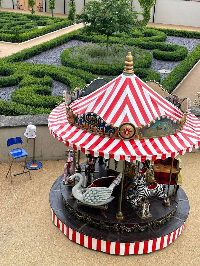 aufnahme von oben von einem karussell mit rot weissem dach. zu sehen ist ein schwan und zebra auf dem karussell.