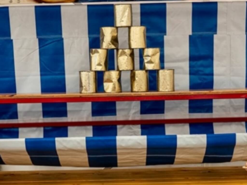 Goldene Dosen sind zu einer Pyramide auf einem blau-weißen Dosenwerfen Aufsatz gestapelt.