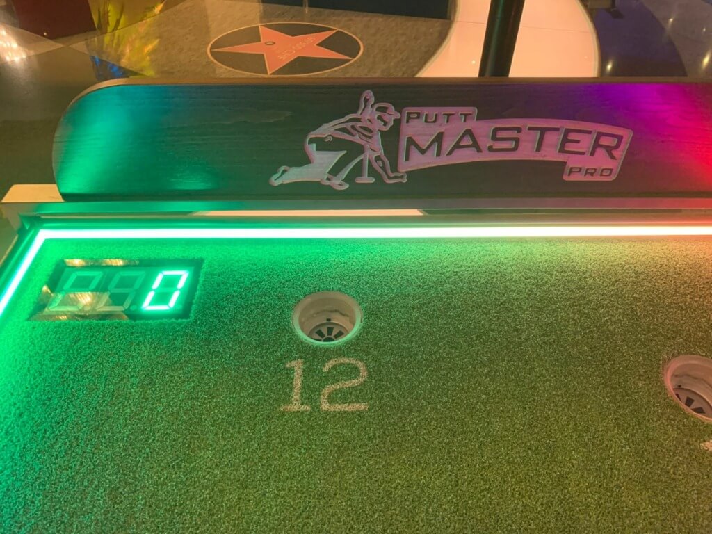 Nahaufnahme der Golf Putting Bahn mit beleuchtetem digitalen Punktestand und Loch Nummer 12.