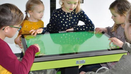 4 kinder spielen am 4touch spieltisch in einem Hotel.