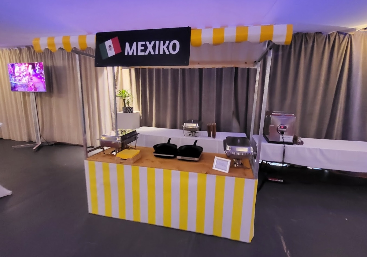 Marktstand mit gelb weiss gestreiftem dach vor schöner Kulisse.