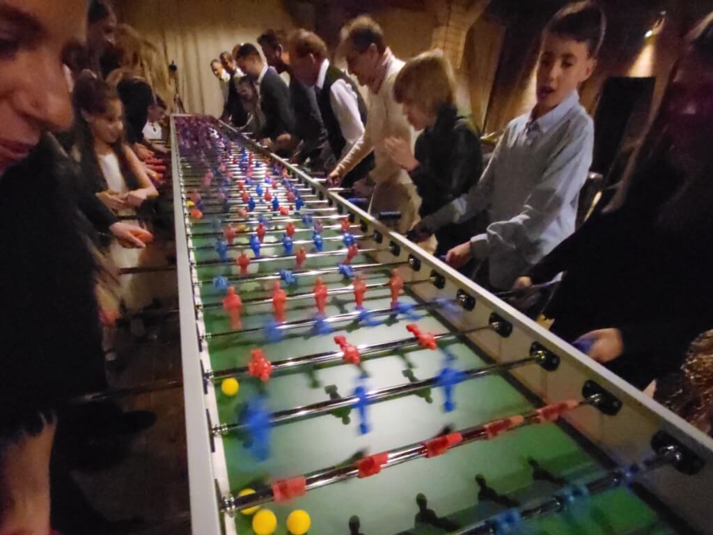 Eine große Gruppe spielt gemeinsam an einem überdimensionalen Tischfussballtisch mit vielen Spielern und bunten Figuren.