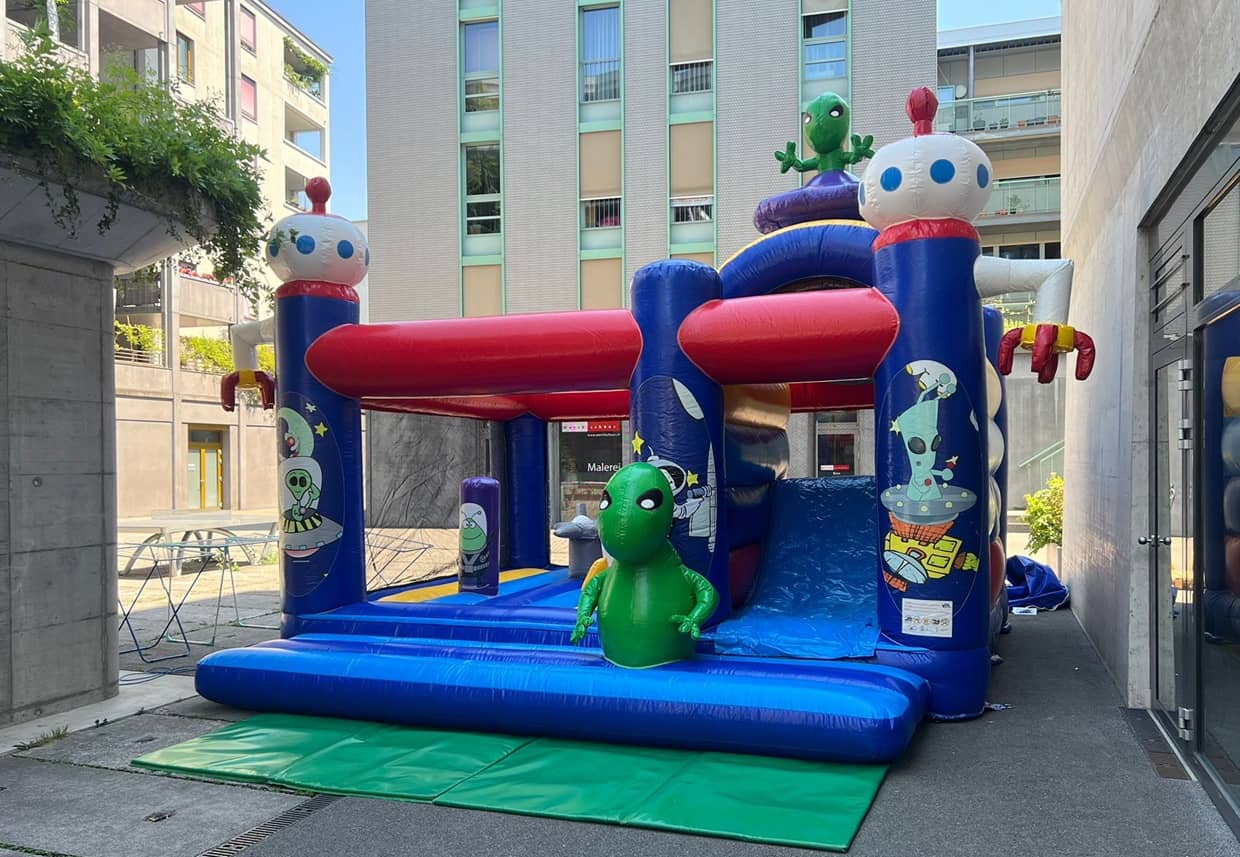 bunte hüpfburg mit einem alien oben drauf.
