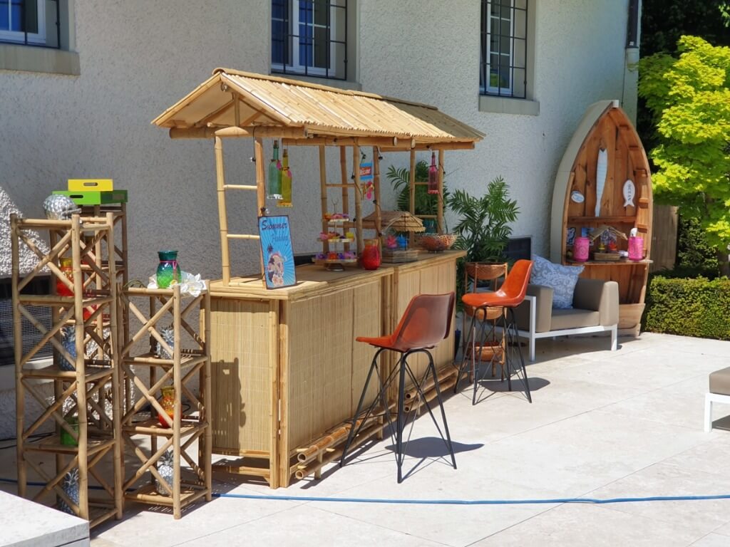 Bambus Bar mit Strohdach und farbenfrohen Deko-Elementen auf einer sonnigen Terrasse