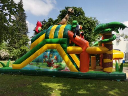 Bunte aufblasbare Hindernisbahn mit Dschungel- und Tiermotiven bei Sonnenschein im Garten
