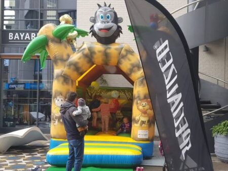 Aufblasbare Hüpfburg im Dschungel-Stil mit mehreren Kindern, betreut von einem Erwachsenen.