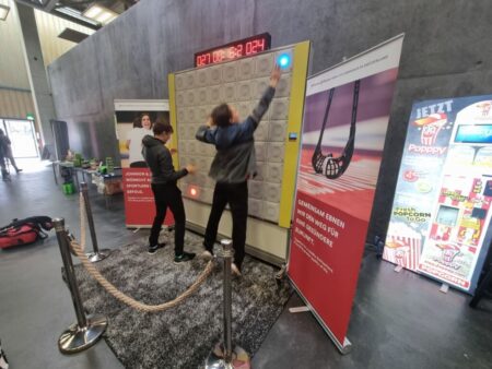 Zwei Personen spielen aktiv an der twall®64-Reaktionswand mit 64 Tastenfeldern in einer Eventhalle.