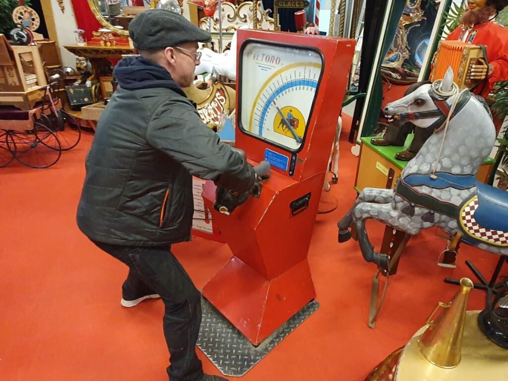 Mann testet seine Kraft an der mechanischen El Toro Kraftmaschine mit Stierhörnern.