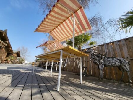 Marktstand Valencia mit rot-weiß gestreiftem PVC-Dach und Holztisch in einem Außenbereich mit Holzboden.