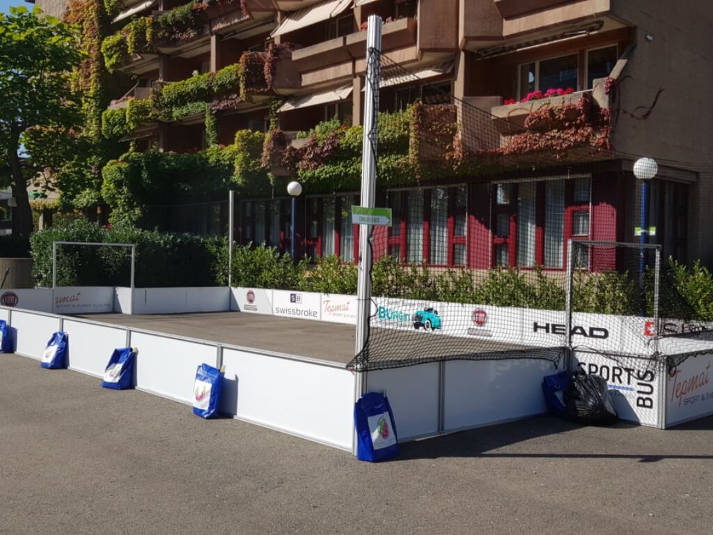 Mobiler Streetsoccer Court mit Seitenbanden und Fangnetz vor einem Gebäude im Freien