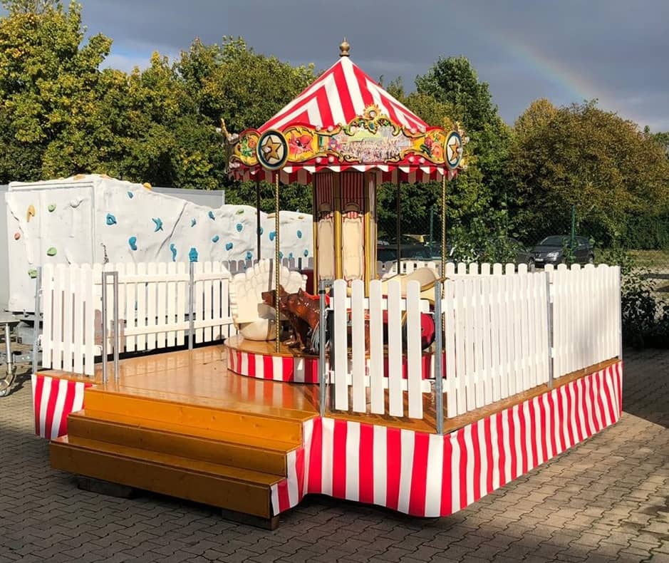 nostalgie karussell auf einem anhänger, rot weisse rundumplane, rot weisses dach.