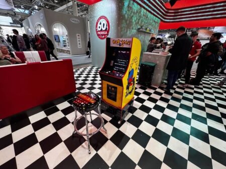 arcade spielautomat pac man mit bistro stuhl davor aud schwarz weiss gekacheltem boden.