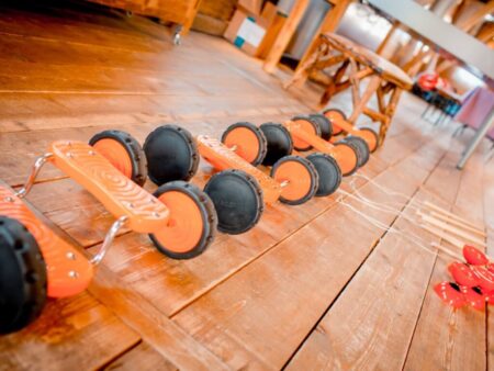 Mehrere orangefarbene Pedalos liegen auf einem Holzboden bereit zum Mieten.
