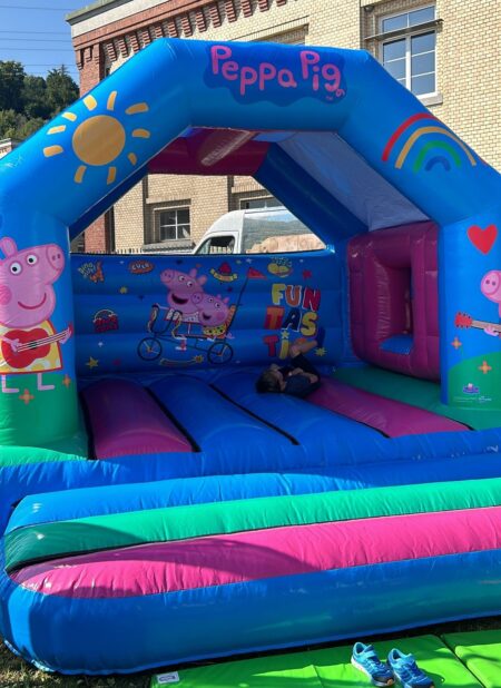 bunte peppa wutz hüpfburg auf einem rasen. keine kinder zu sehen bisher.