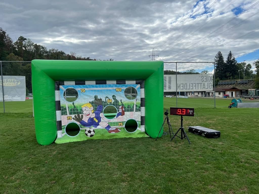 aufblasbare grüne torwand auf einem rasen. Links daneben die Radar Anzeige auf einem Ständer.