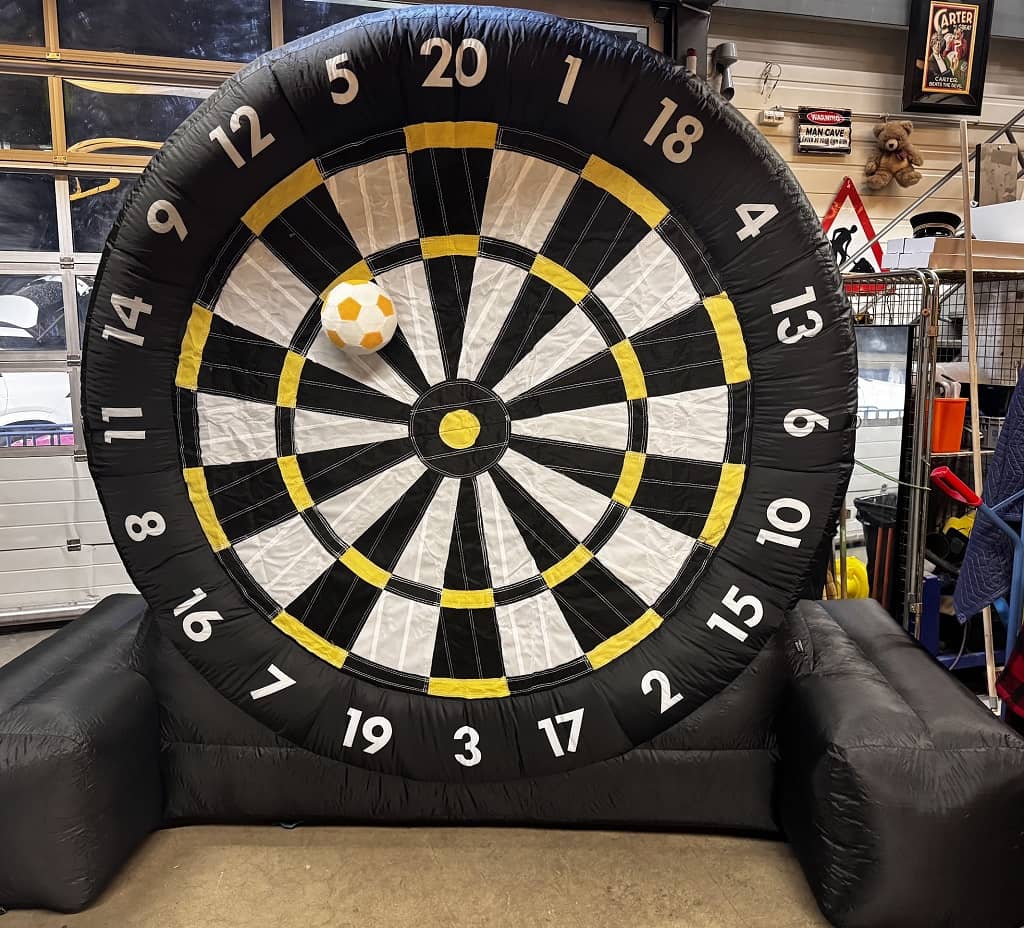 aufblasbare riesen dartscheibe mit 200 cm durchmesser. diese steht in einer halle. an ihr klettet ein fussball.