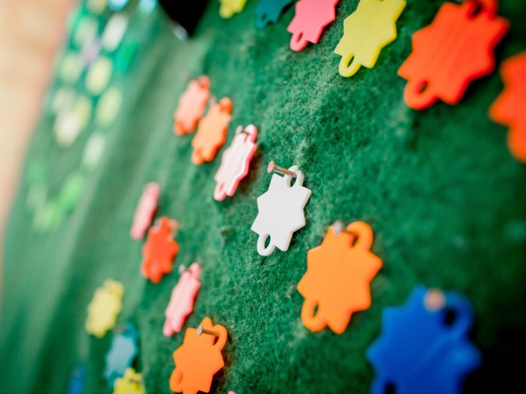 Bunte sternförmige Zielmarker aus Kunststoff auf grünem Filz, befestigt mit kleinen Nägeln.