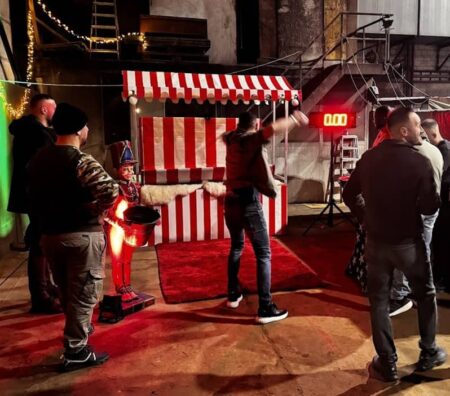 eine person wirft einen schneeball in eine vorrichtung. 4 weitere stehen drumherum und schauen zu.