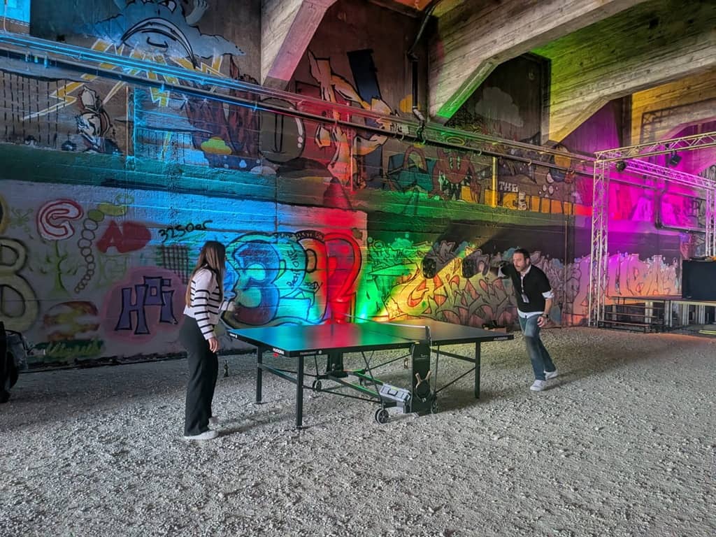 in einem bunt beleuchteten tunnel spielen 2 personen ein tischtennismatch.