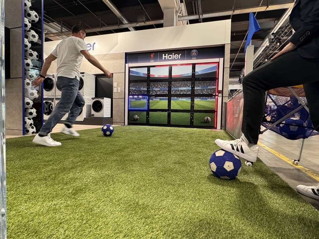 Spieler spielt an der Sutu Torwand auf einer Messe. Untergrund ist grüner Kunstrasen.