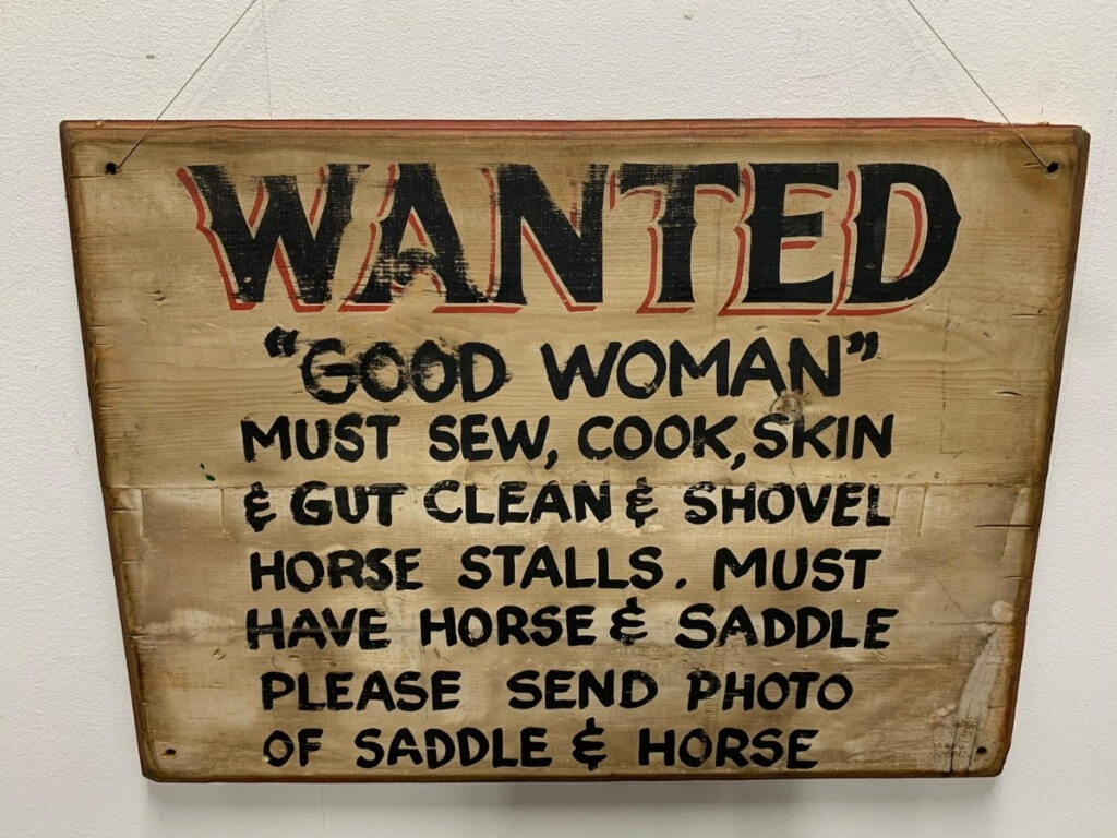 Rustikales Holzschild mit der schwarz-roten Aufschrift Wanted und weiteren Jobanforderungen im Westernstil.