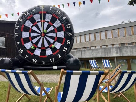 riesen grosses aufblasbares dart, davor 3 blau weisse liegestühle.
