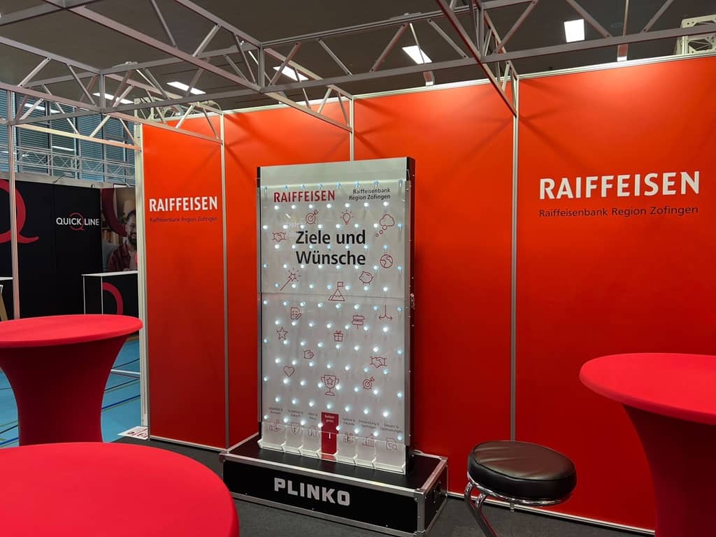 beleuchtetes xxl plinko am messestand der raiffeisenbank vor rotem hintergrund.
