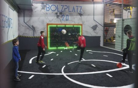 Kinder spielen in eienr Halle an der SUTU interaktiven Fussballwand.