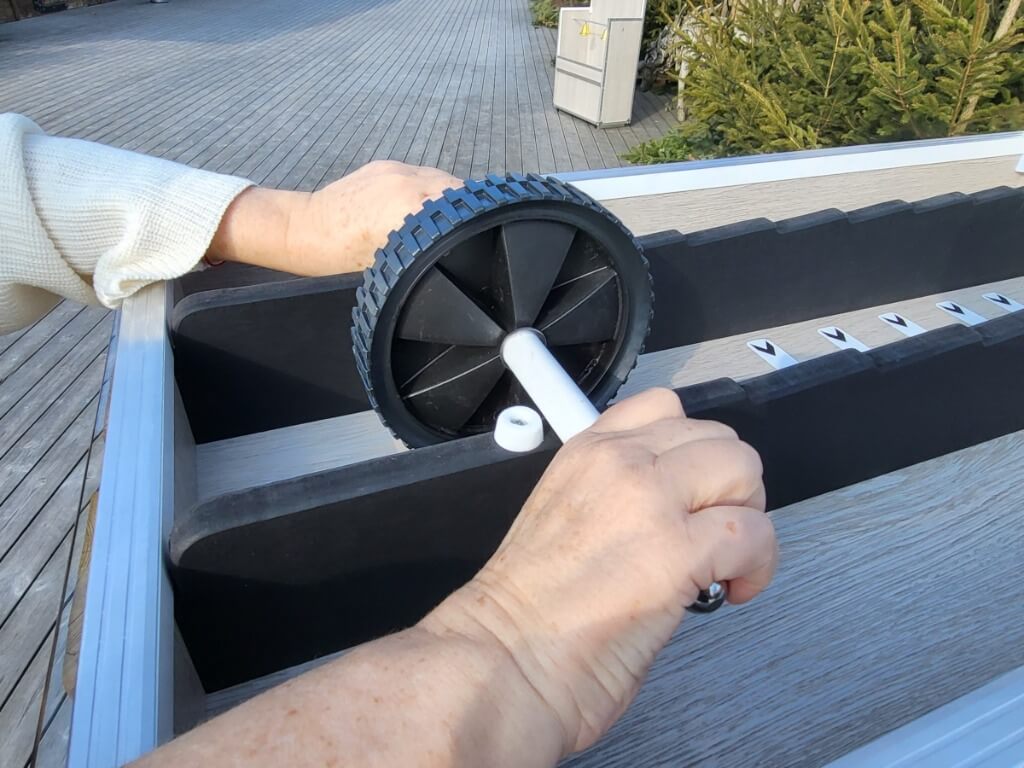 Person dreht den schwarzen Zahlenroller bei einem Geschicklichkeitsspiel auf einem Holztisch.