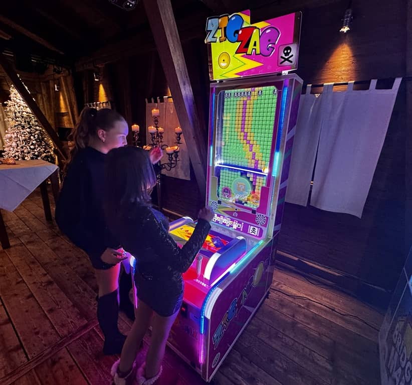 2 junge damen spielen am zog zag spielautomaten.